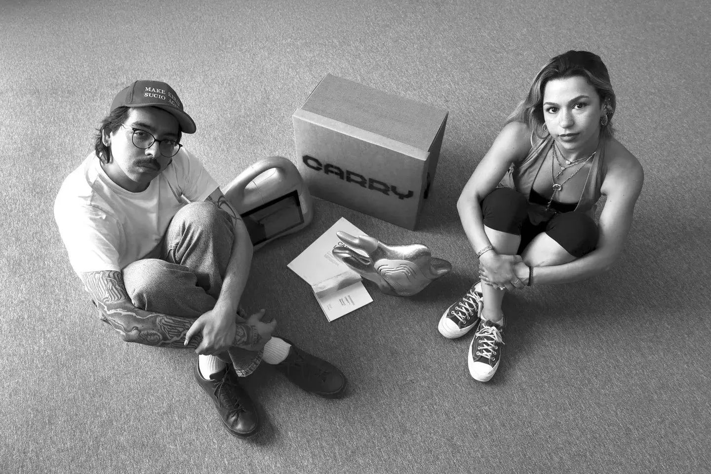 The creators of CARRY seated with the briefcase, its shipping box, the chrome hand, and the owner's manual.